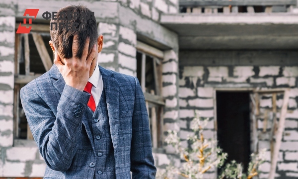 мужчина смотрит на недостроенный дом с грустью