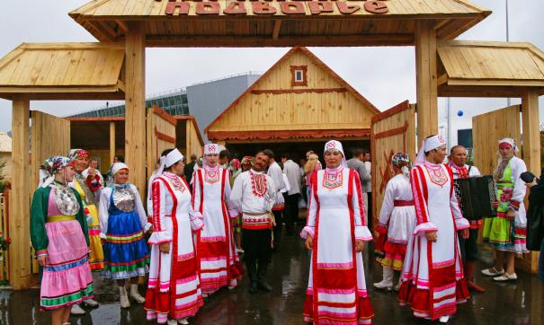 Марийцы в народных костюмах под аркой с надписью Марийское подворье
