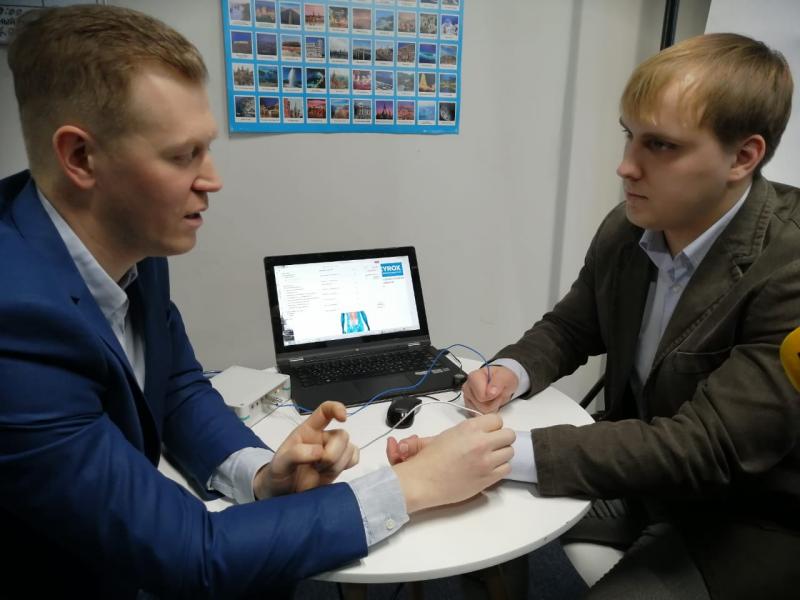 Юрий Корюкалов (слева) показывает на добровольце работу аппарата для физиотерапии