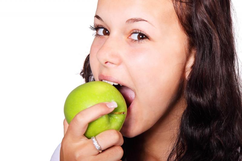 Девушка жует яблоко