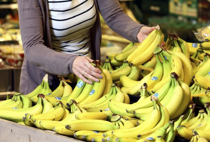 Женщина покупает бананы