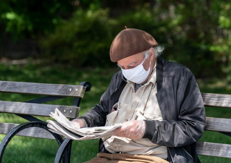 Дед в маске на лавочке читает газету