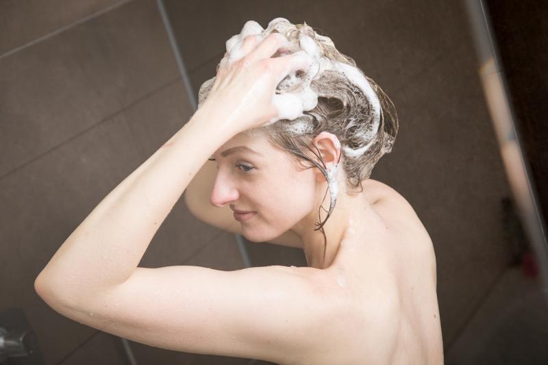 женщина моет голову шампунем