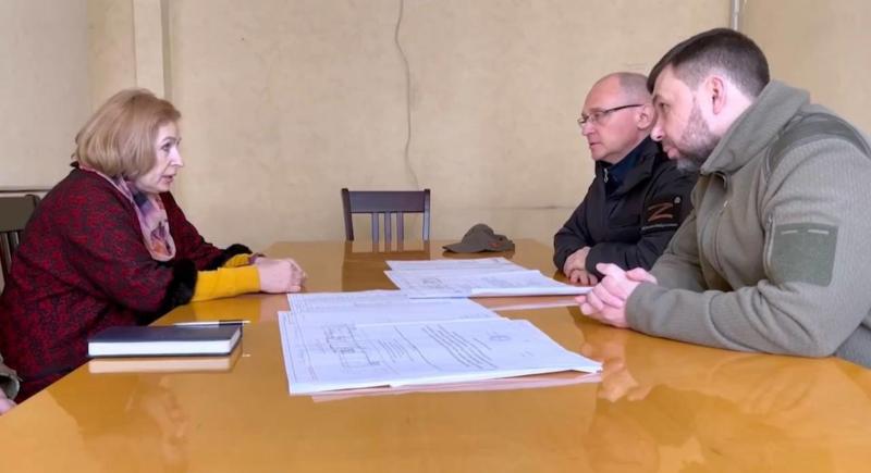 Денис Пушилин и Сергей Кириенко сидят за столом и разговаривают с женщиной