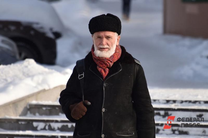 Пожилой мужчина пенсионер с седой бородой в зимнем тулупе и шапке