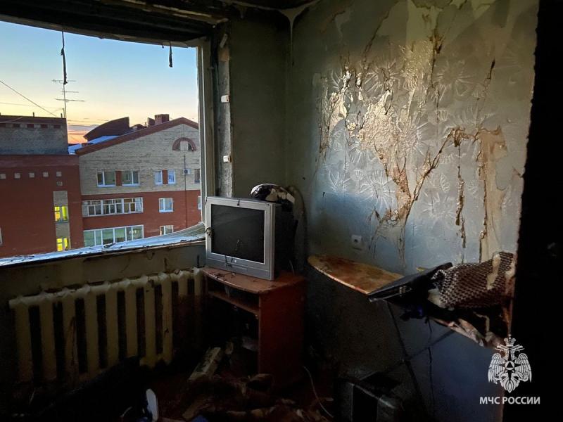 Комната с вещами и телевизором, с выбитыми окнами и поврежденными взрывом обоями