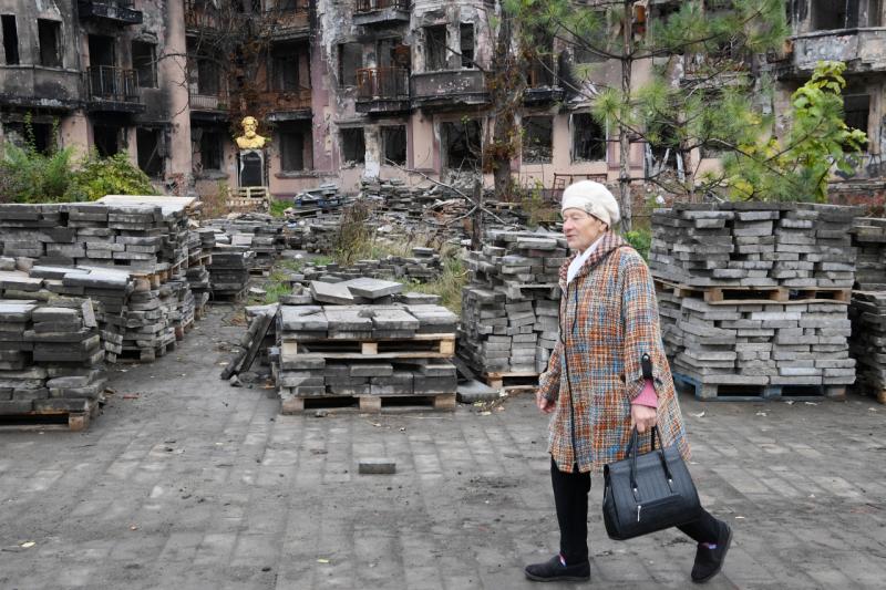 Пожилая женщина на фоне разрушенного здания в Енакиево