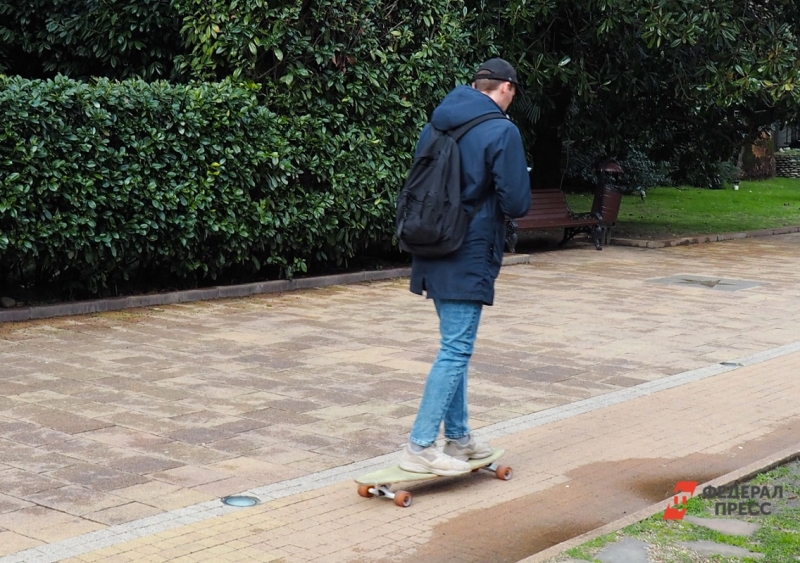 Подросток едет на скейтборде по улице