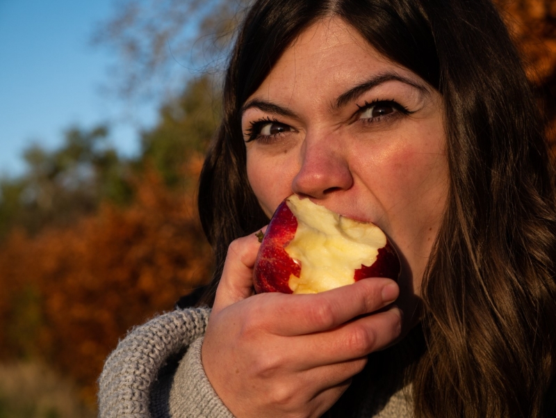 Девушка ест красное яблоко
