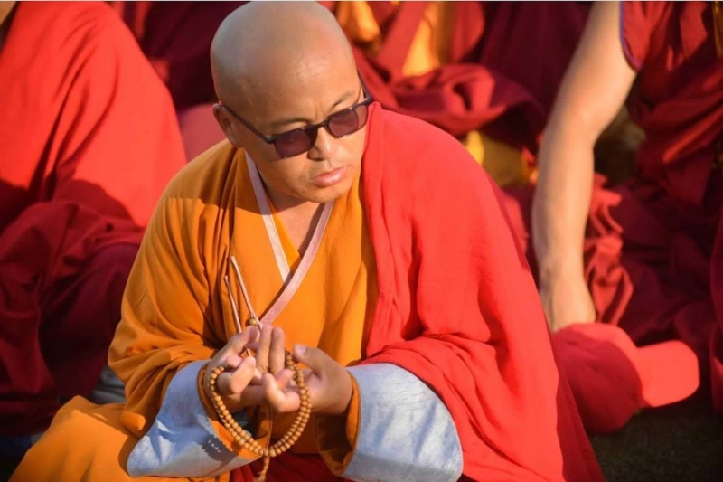 Буддийский монах в традиционных одеждах с четками в руках