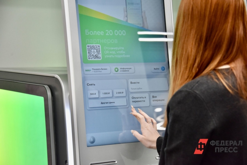 Женщина снимает наличные рубли в банкомате