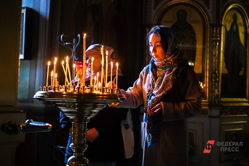 Девушка ставит свечу в православном храме