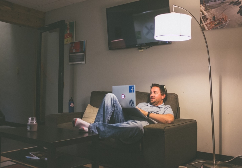 Мужчина сидит в компьютере при искусственном освещении