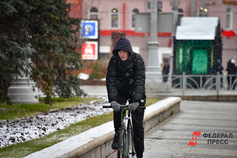 Молодой человек едет на велосипеде в снег