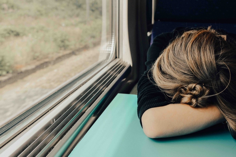 Девушка спит, положив голову на стол в поезде