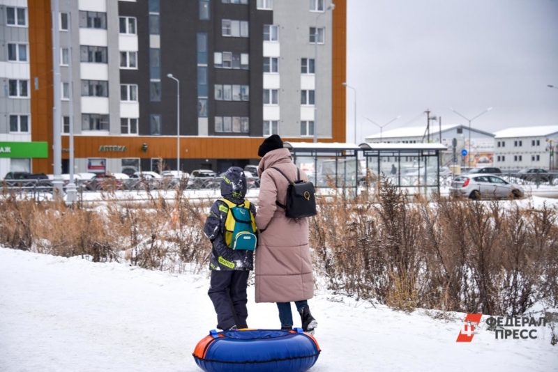 Женщина с ребенком гуляет во дворе зимой