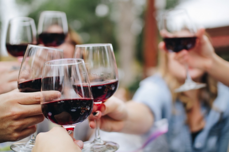 Люди чокаются бокалами с красным вином
