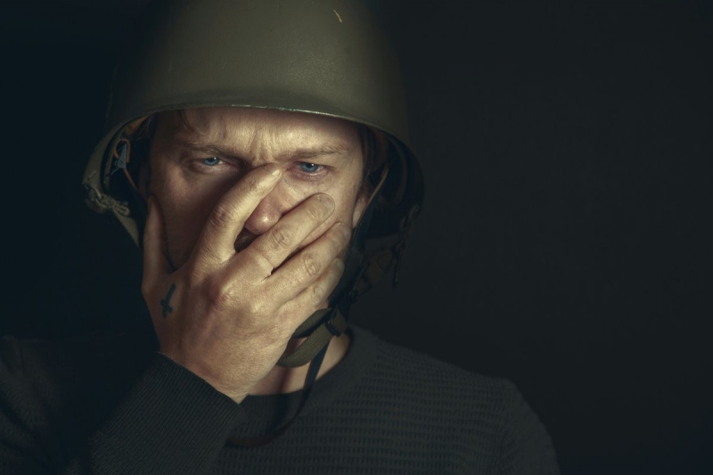 Украинский солдат с рукой у лица