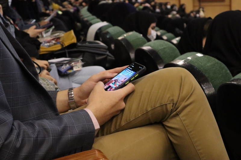 Молодой человек использует смартфон на конференции