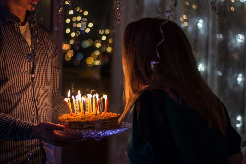 Девушка задувает свечи на торте