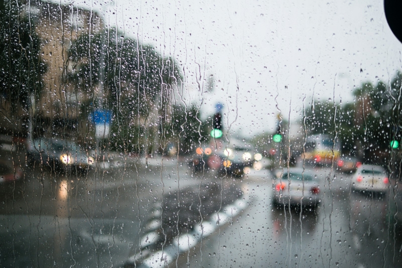 Вид на улицу через стекло, усыпанное каплями дождя