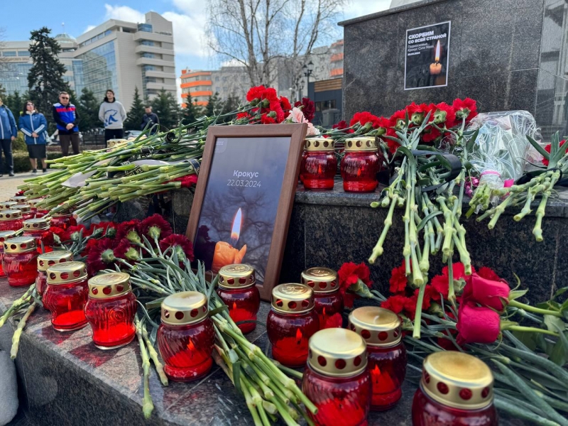 Люди приносят цветы и свечи к посольствам России