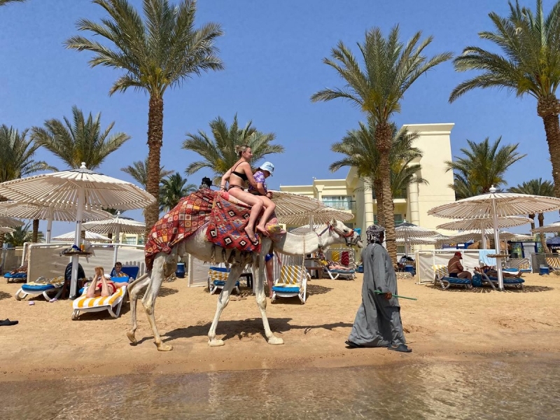 Женщина едет на верблюде на курорте