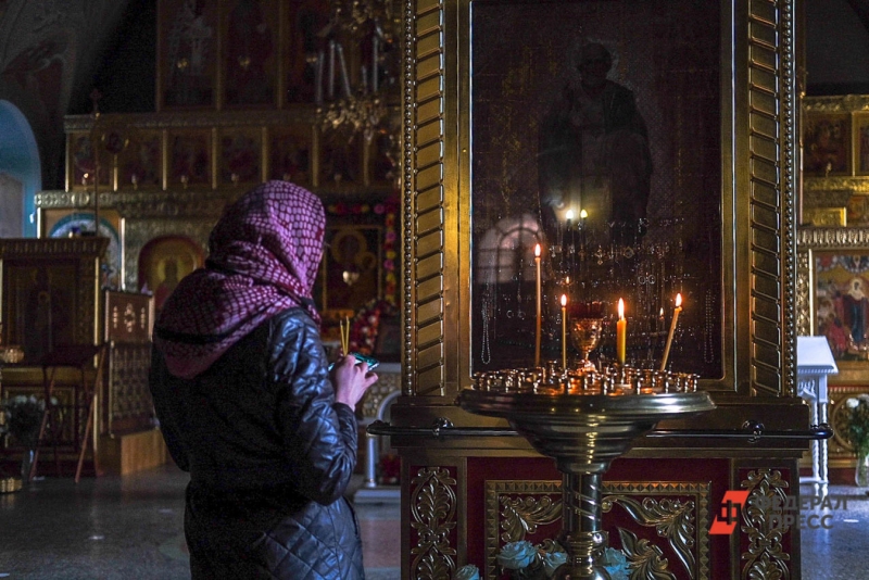 Женщина ставит свечку в храме
