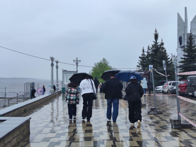 Люди гуляют по набережной в дождь
