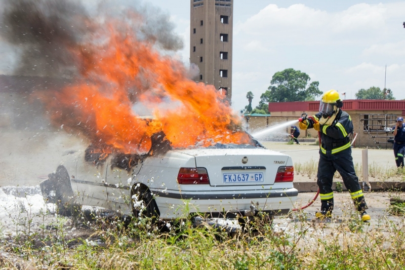 пожарный тушит горящий автомобиль