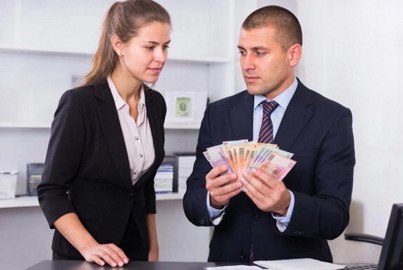 Мужчина несет деньги женщине в банк